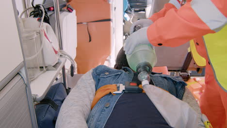 male paramedic helping an injured african-american patient using respiratory equipment in the ambulance