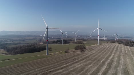 Wind-mills-in-beautiful-field-creating-electricity---aerial-shot