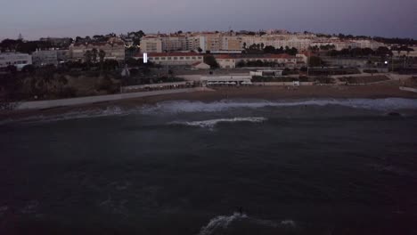 aerial-view-of-Surfer-pulls-a-huge-turn-on-the-crest-of-a-big-wave-at-night-time-in-the-Portugal-in-Cascais,-Estoril