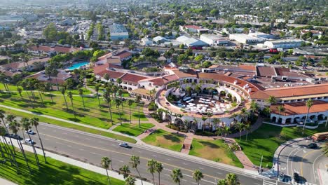 Drone-flying-along-coastline-at-sunset-showing-ocean,-hotel,-city-and-mountains