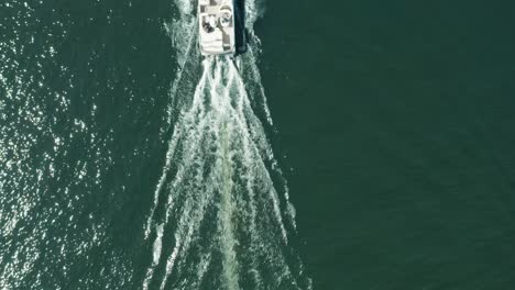 Aerial-top-down,-pontoon-boat-with-family-and-friends-relaxing-sailing-on-lake-during-summer-vacation