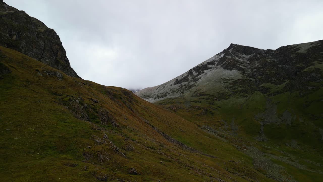 Grass-covered hillside transitions into a towering snowy summit