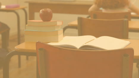 pow text on speech bubble against stack of books and apple on school desk