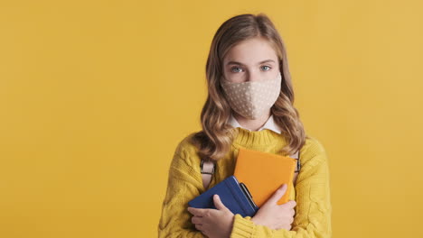 teenage caucasian girl with face mask holding books.