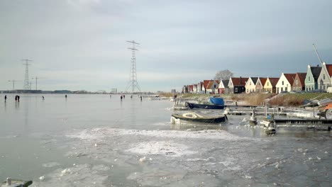 traditional dutch village durgerdam in the rare white winter with frozen pond and people ice skating on it, amsterdam, netherland