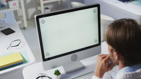 médico caucásico que realiza una consulta por videollamada utilizando una computadora de escritorio