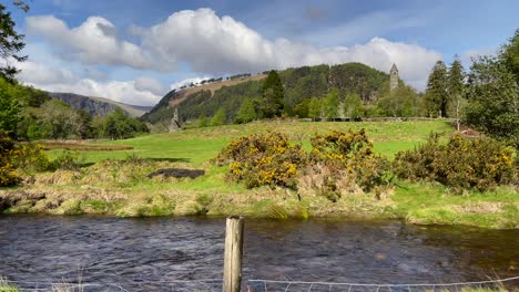 panoramic footage of medieval monastery ruins in the background, with a stream flowing in the foreground