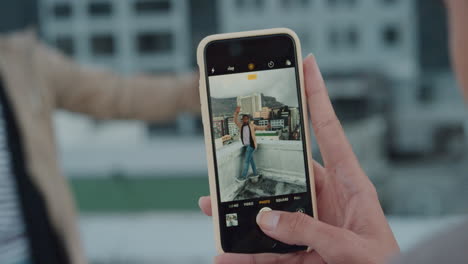 mujer de cerca usando un teléfono inteligente tomando una foto de un amigo posando haciendo caras divertidas disfrutando de una fiesta en la azotea al atardecer divirtiéndose compartiendo un fin de semana loco en la ciudad en las redes sociales
