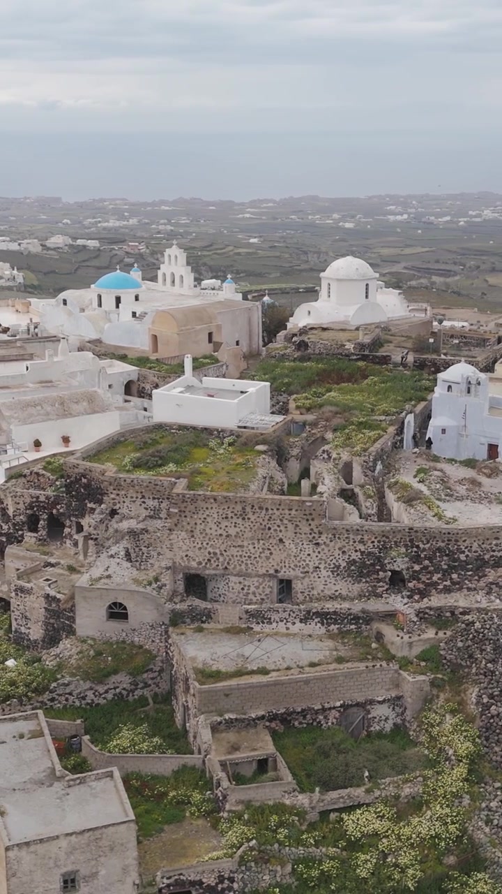 Veduta aerea verticale dello storico Castello di Pyrgos e del villaggio imbiancato a calce circostante a Santorini, Grecia