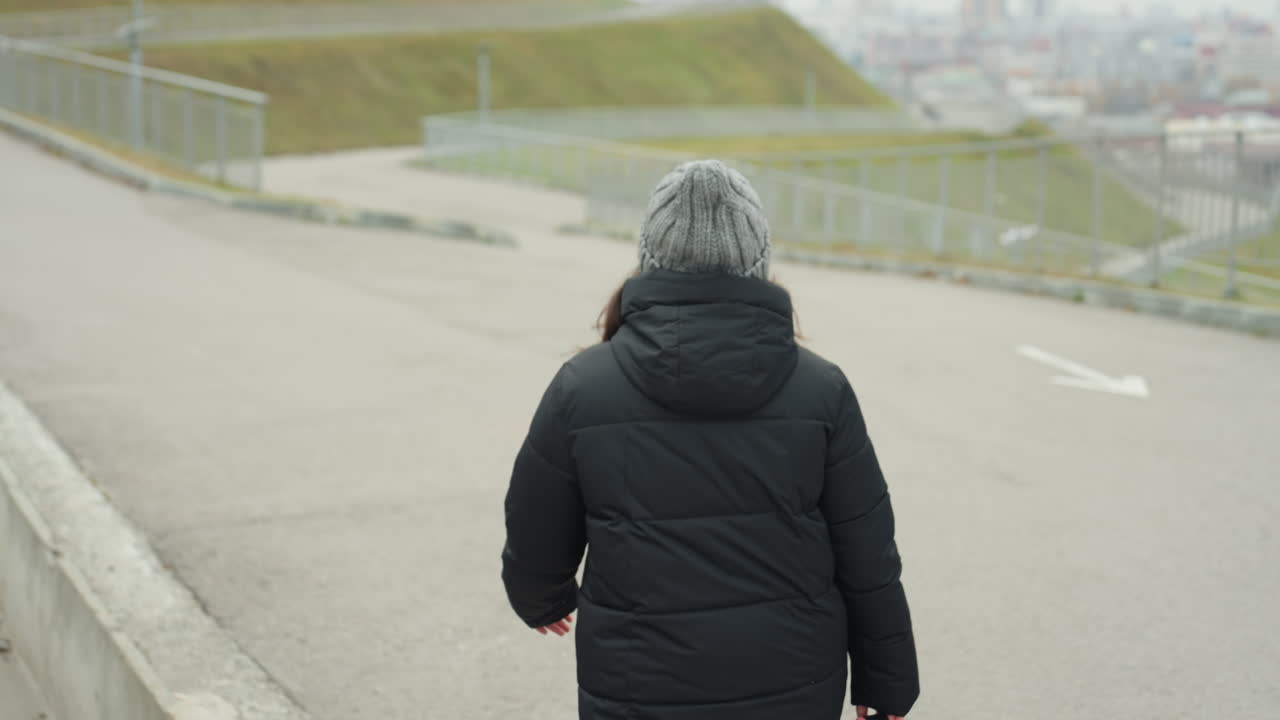 Single woman moves down empty city street. Woman proceeds calmly along deserted urban thoroughfare completely alone. Solitary female journeys steadily amid silent cityscape on quiet urban road