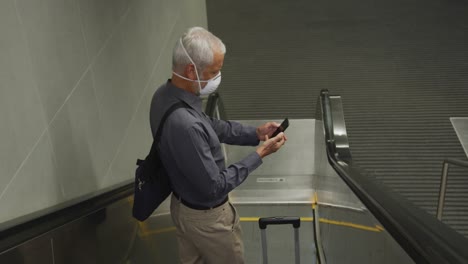 caucasian man out and about in a metro station wearing on a face mask against coronavirus