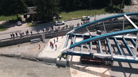 bridge construction: aerial view of a steel arch bridge being lifted into place