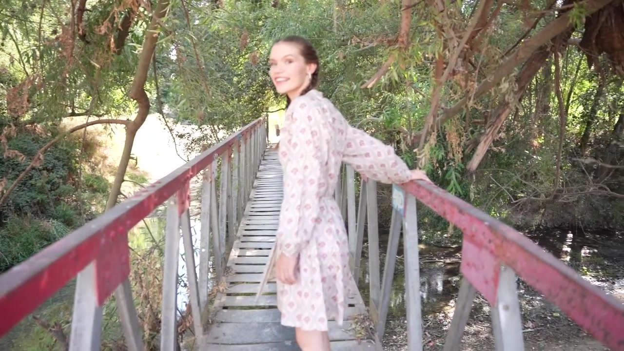 Una donna osserva pacificamente la bellezza della natura stando su un suggestivo ponte di legno.