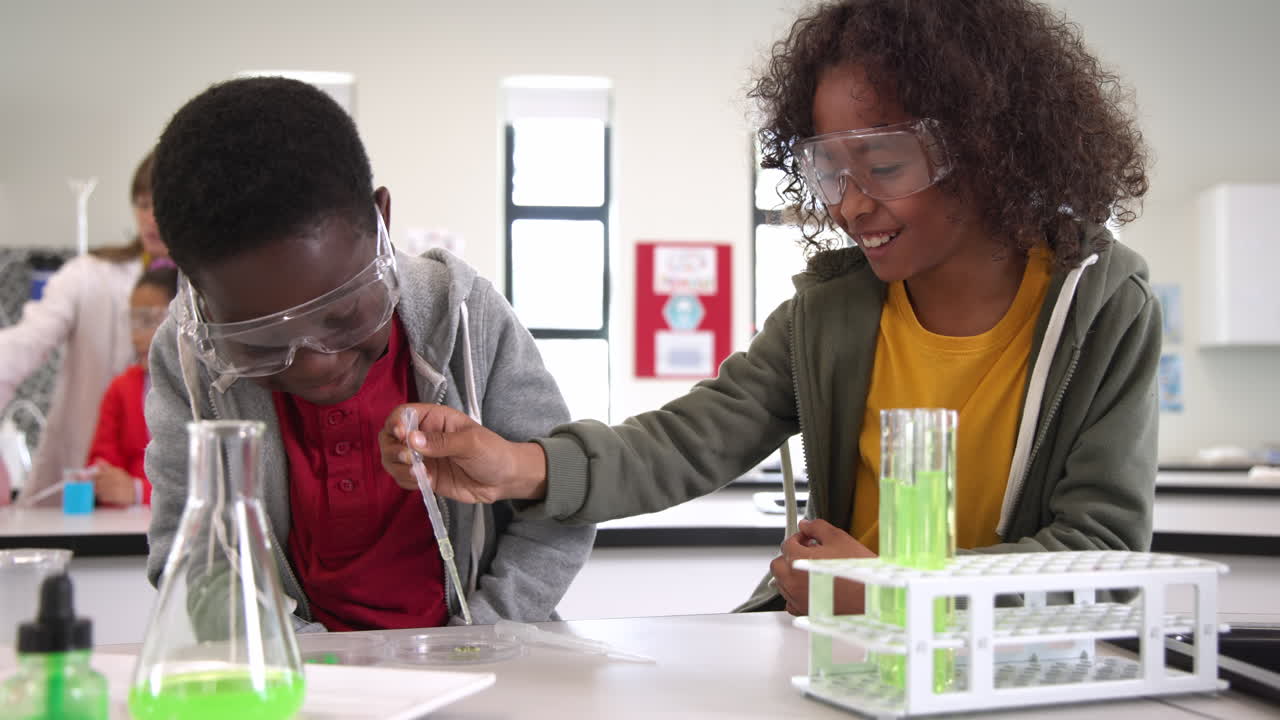 Children conducting science experiment in classroom, using pipette and test tubes