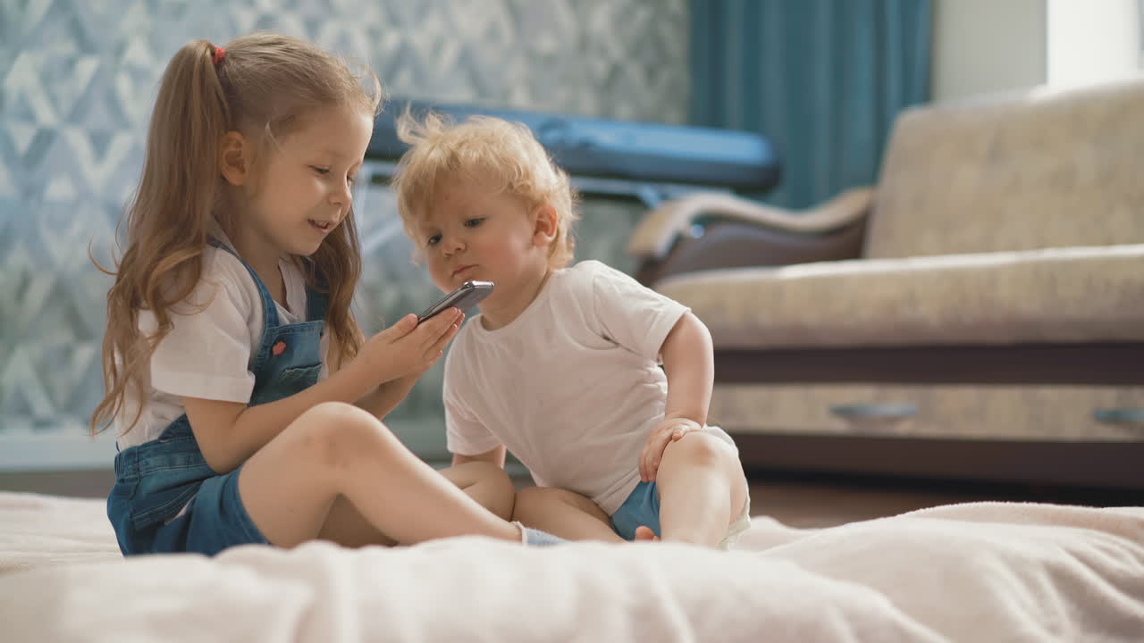 niño bebe agua sentado cerca de la hermana mayor con teléfono móvil