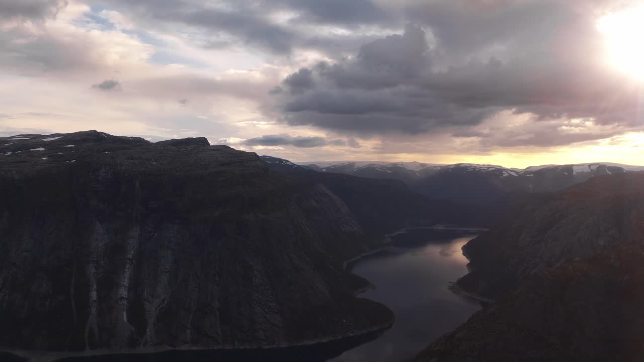 A woman running up to a cliff in Norway, surrounded by a scenic landscape with mountains, Trolltunga