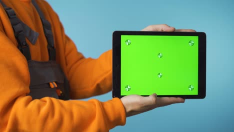 reparador con una tableta de pantalla verde en la mano