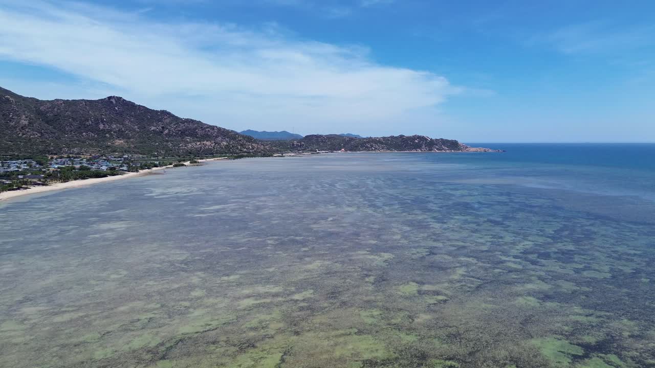 Drone flight forward over My Hoa Lagoon, showcasing the extensive shoreline and clear coastal waters in the midday sun. My Hoa Vietnam, famous kitesurfing spot during low season.