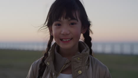 portrait of little asian girl smiling cheerful enjoying happy summer vacation on seaside park