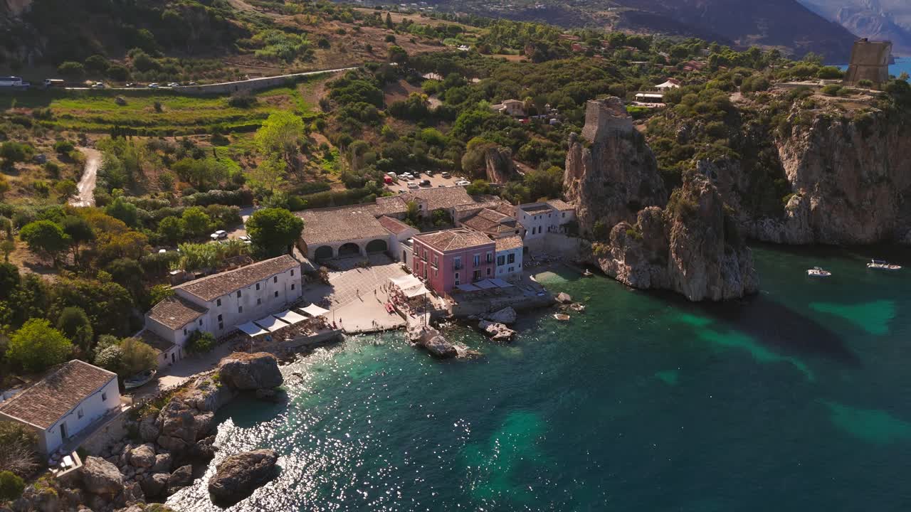 Static aerial drone view of Tonnara di Scopello and turquoise water on the rocky Sicilian coast during summer