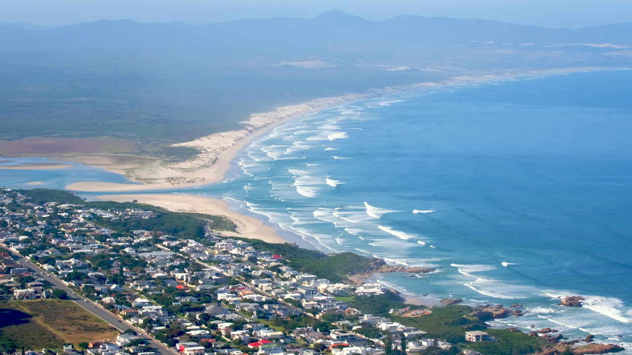Panoramic Aerial View of a Coastal Town, Sandy Beach, and Ocean Waves