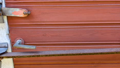 4K-60FPS-Metal-Bar-and-Two-Pad-Locks-on-Red-Door-on-Old-Shed---Truck-Shot