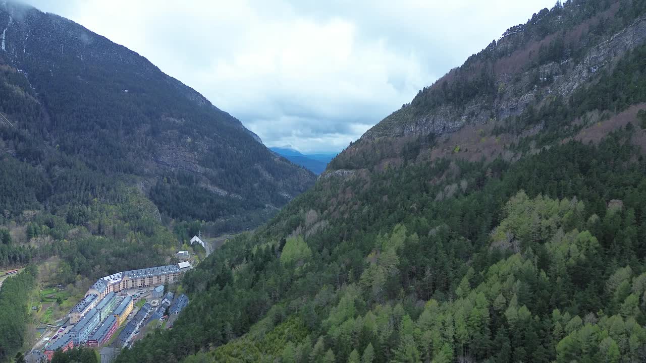 Canfranc-estación, a historic railway station surrounded by mountains and forests, aerial view