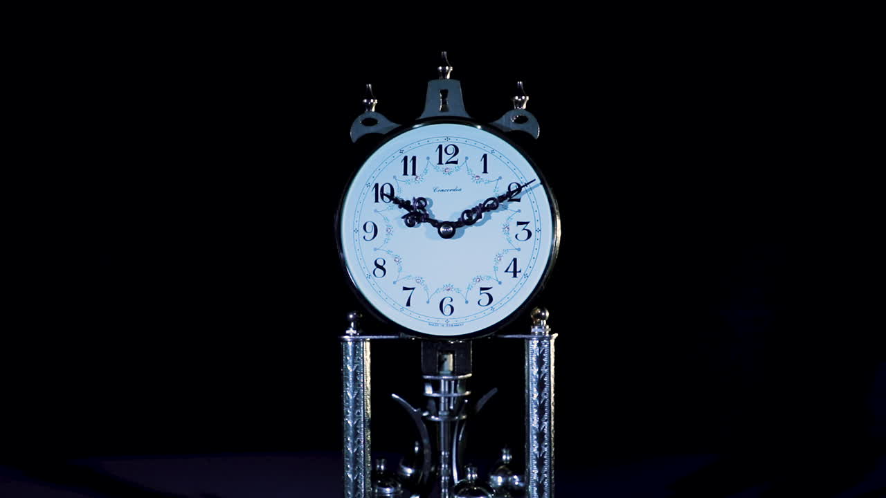 close up of an old clock in low key studio lighting, backward dolly
