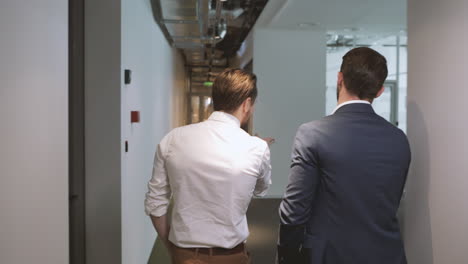 Following-two-unrecognizable-businessmen-through-the-hallway-of-an-office-building
