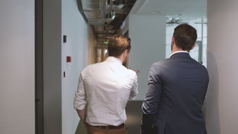 following two unrecognizable businessmen through the hallway of an office building