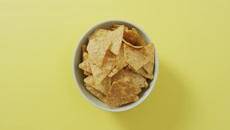 acercamiento de nachos en un tazón con espacio de copia en la superficie amarilla