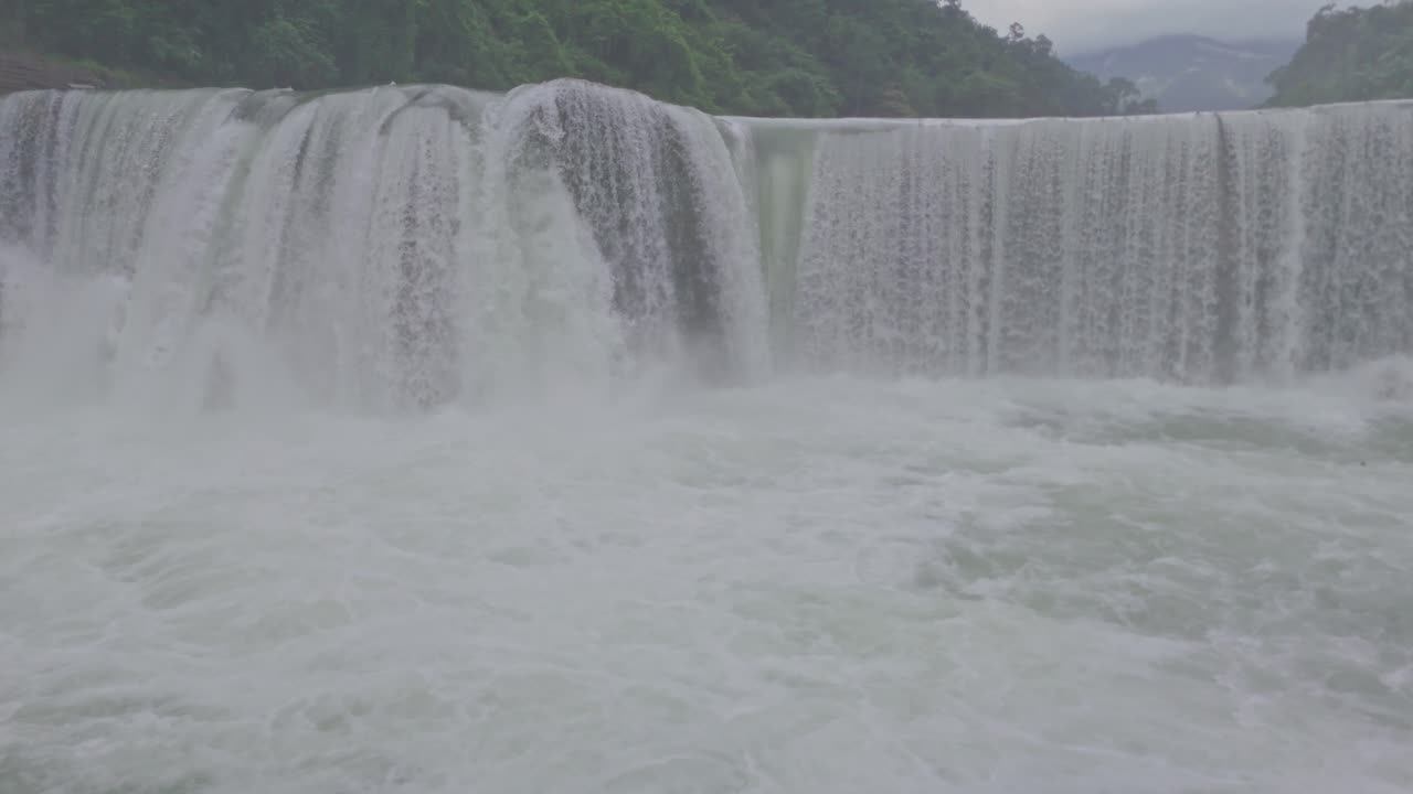 A breathtaking aerial view of a beautiful waterfall cascading through lush green mountains, showcasing the untouched beauty of nature, flowing water, and serene landscape scenery