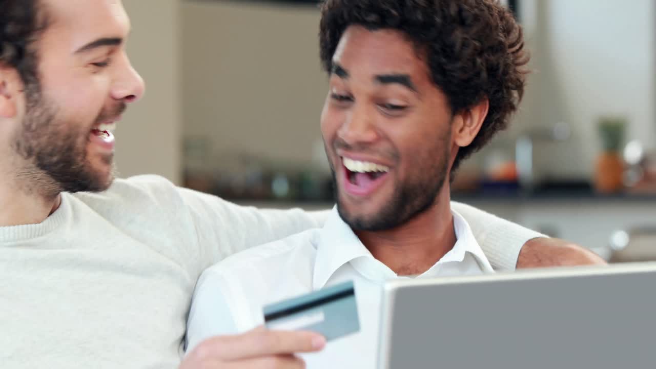 Gay couple relaxing on the couch using laptop