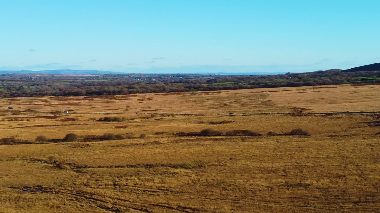 Orbiting Aerial View of Rural Countryside Road Surrounding by Natural Landscape as Car Drives to Destination with Mountains in Deep Background. Filmed in Gower in South Wales, UK