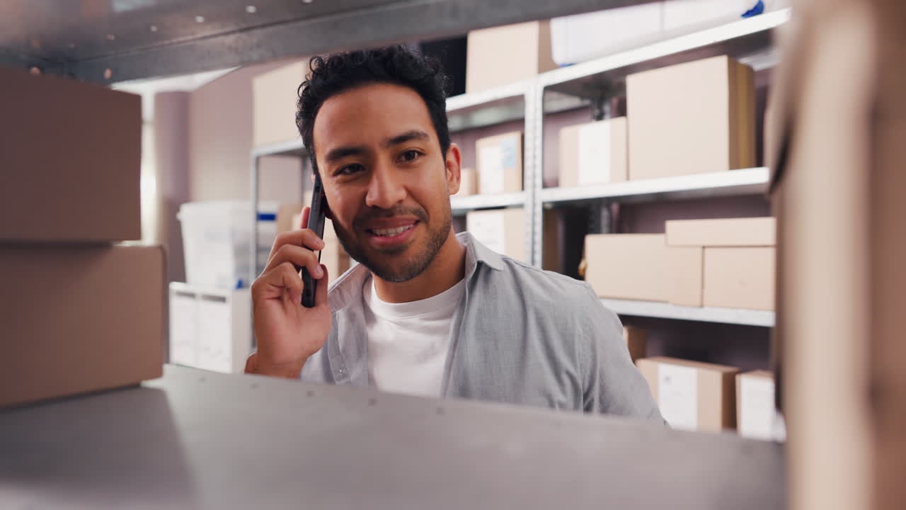 Man Talking on Phone While Checking Inventory in Warehouse