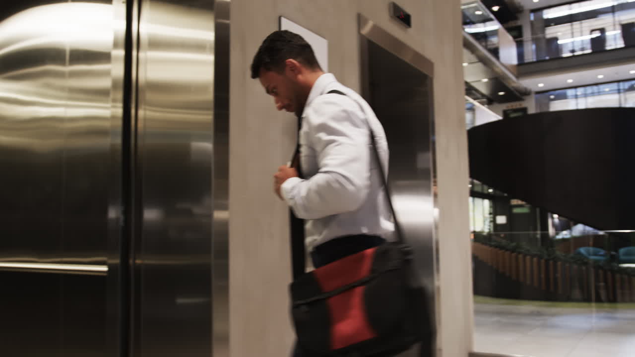Entering elevator, businessman in formal attire carrying bag in office building