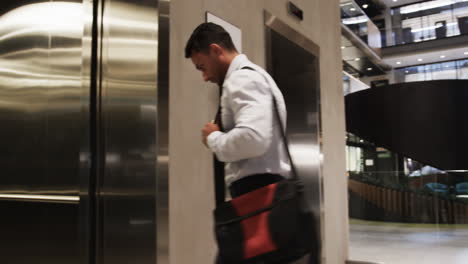 entering elevator, businessman in formal attire carrying bag in office building