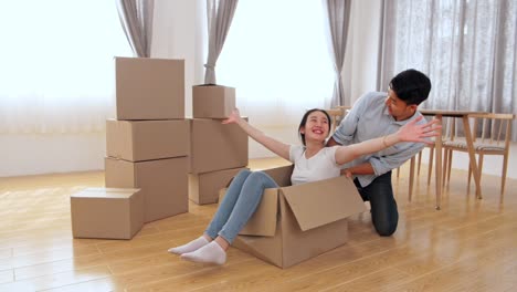 happy couple is having fun with cardboard boxes in new house at moving day