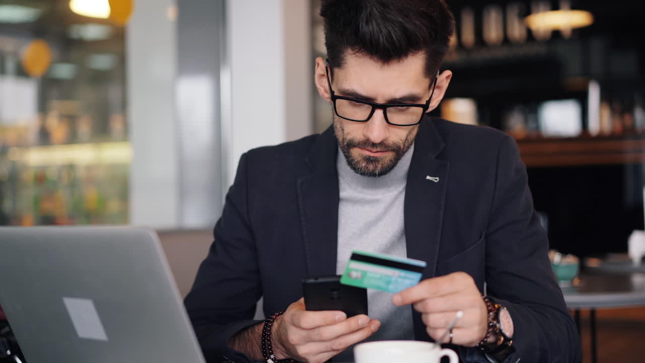 Man using credit card and smartphone in a coffee shop