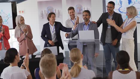 male speaker and applauding audience and colleagues at a business conference