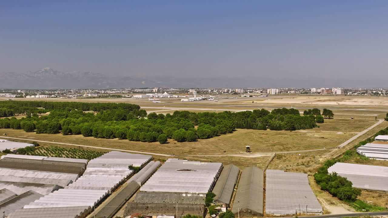antalya turquía antena v55 sobrevuelo bajo barrio yenigöl capturando agricultura hortícola con estructuras de invernadero, aeropuerto internacional en el fondo - filmado con cine mavic 3 - julio de 2022