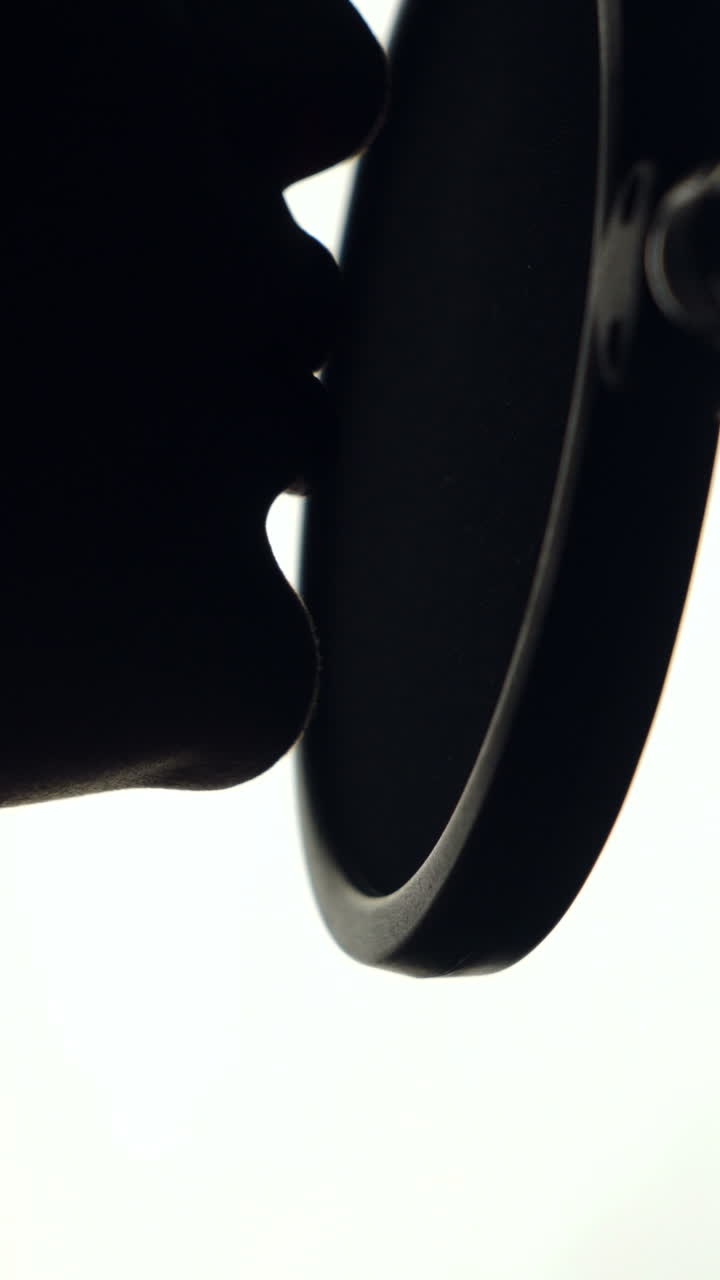 woman is recording a song in an audio studio. The silhouette of a woman's face is singing a song on the white background. Close-up Vertical video