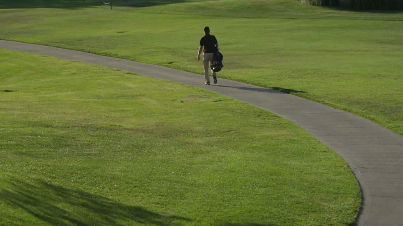 A golfer walks along a path on a golf course