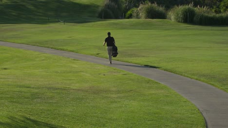 un golfista camina por un sendero en un campo de golf