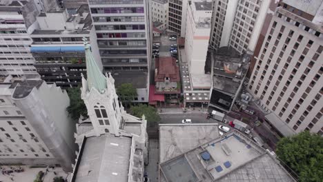 urban aerial pulls up from old building surrounded by tall skyscrapers