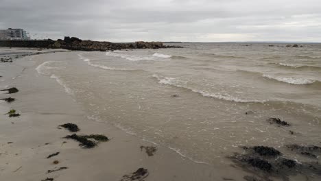 Vista-Estática-De-La-Playa-De-Damas-Con-Algas-Marinas-Que-Se-Lavan-En-Tierra-En-Suaves-Olas,-Galway-Irlanda