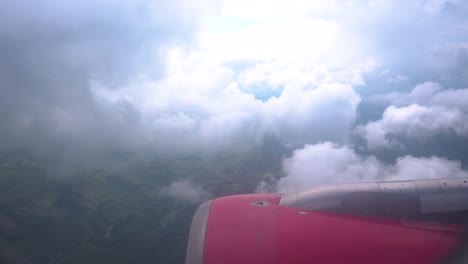 inside airplane cabin looking outside through window with red engine and clouds above earth, bright sunlight, travel by aeroplane, cruising altitude, slow motion