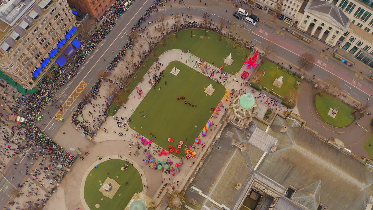Dynamic top-down aerial spin over St. Patrick’s Day performers and crowd at Belfast City Hall