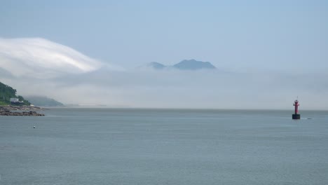 紅色導航浮标漂浮在黃海之間的島<unk>,一個被霧雲覆蓋的山在ganghwado島附近,南韓廣場拍攝靜態