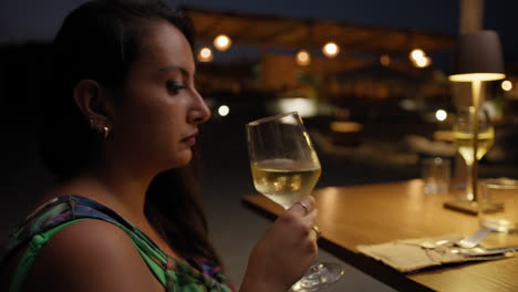 woman grabbing the glass at the restaurant to smell the wine flavour